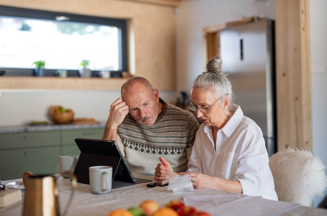 Photograph of senior couple at table reviewing their expenses